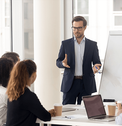 Image of a man in a boardroom talking to a group of professionals.